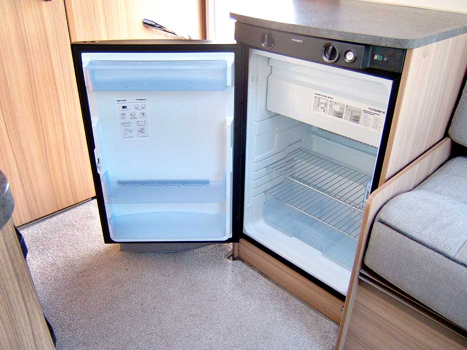 View of the fridge with freezer top box interior that is situated by the entrance / exit door.